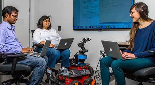 Three researchers work on programming a robot.