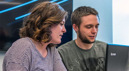 Two students work at a computer.